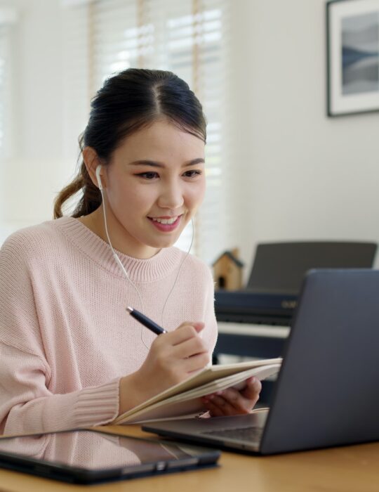 Candid young attractive asian female employee wear earphone listen to digital online